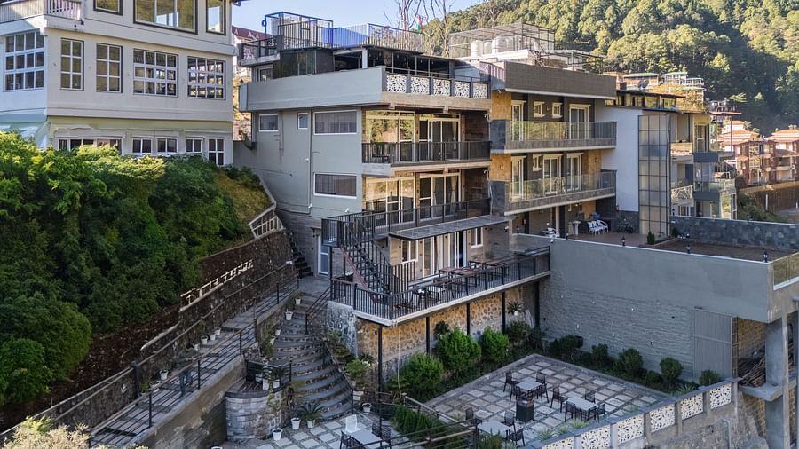 Exterior view of the hotel building with surrounding greenery and hillside landscape in the background.