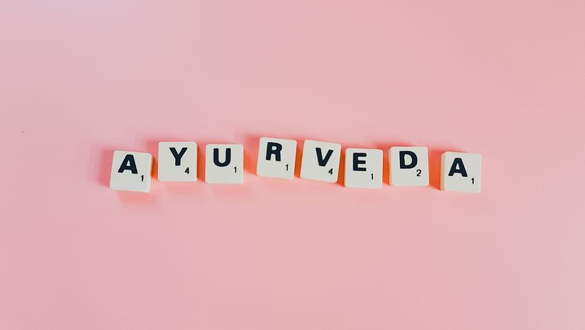 Ayurveda written in scrabble tiles that is placed in a pink table