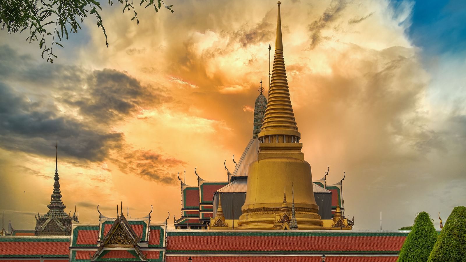 Side view of the Grand Palace in Bangkok with different hues in the sky in the background.