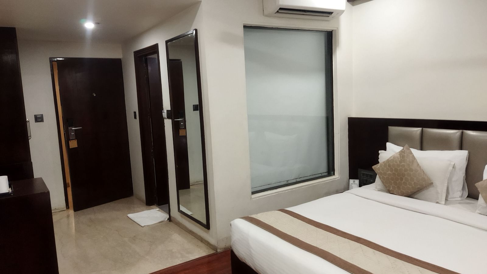 A spacious hotel room with a large window, a queen sized bed and a reflective wardrobe - TGI Apple Inn, Jaipur 
