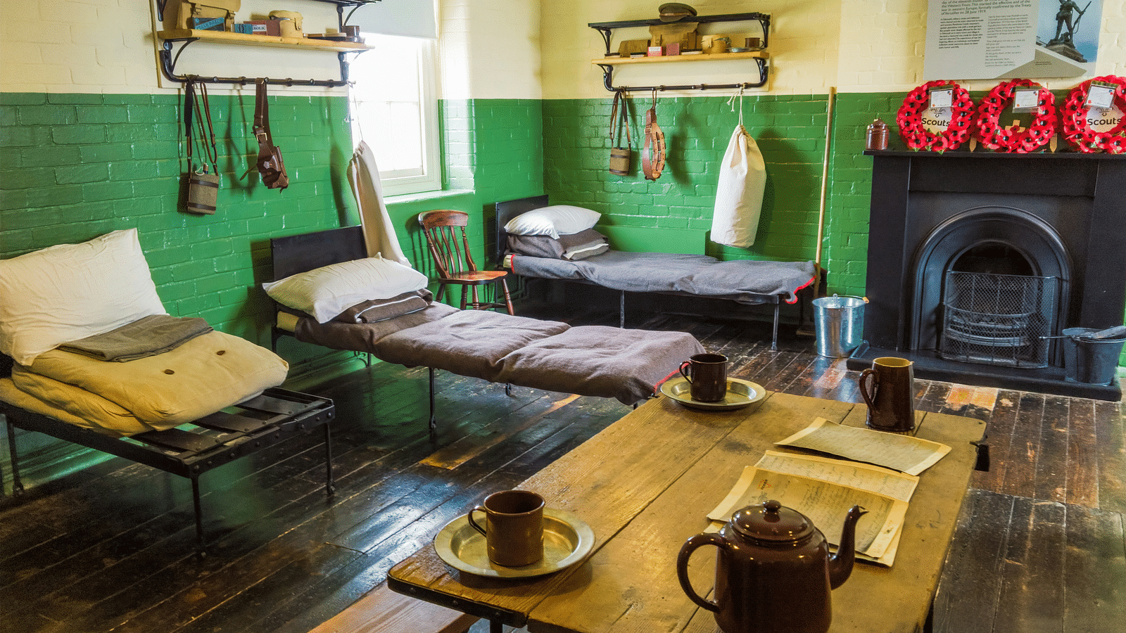 A dormitory room with comfortable beds, a desk and a fire place