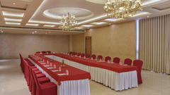 Conference room with long rectangular table and red seating - Pride Elite Gandhinagar