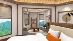 A 2-room suite with a bed in the foreground and a living area with a sofa and windows in the background at Royal Tulip, Chitwan.