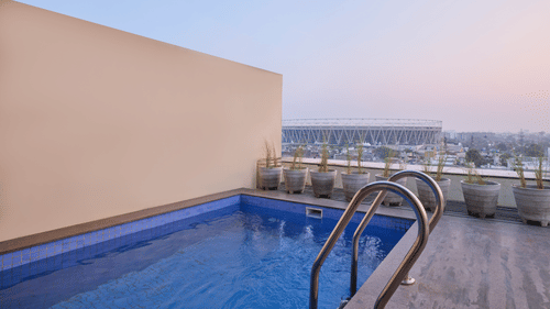 Private rooftop pool with city skyline backdrop at dusk - Biznotel by Pride Motera, Ahmedabad