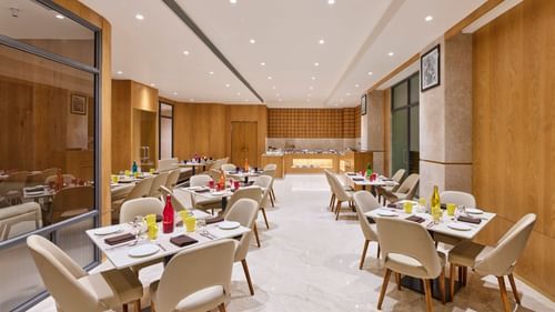 Elegant hotel dining room with set tables, ready for guests to enjoy a meal - Biznotel by Pride Motera, Ahmedabad