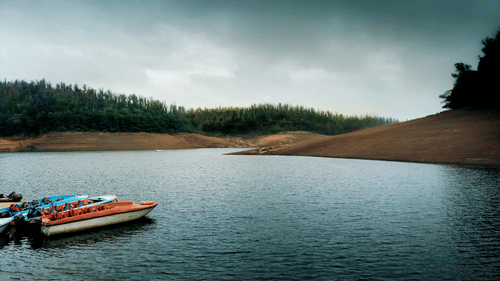 A peaceful view of a lake with a boat gently floating on the calm water under a clear sky.