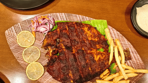 Fried fish and french fries placed on a plate shaped like a leaf.