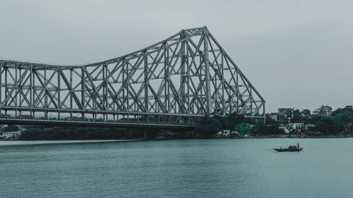 Howrah bridge above a river on a cloudy day.