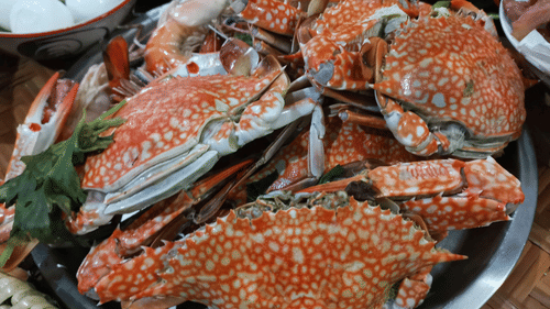 A large pile of steamed blue crabs on a metal platter.