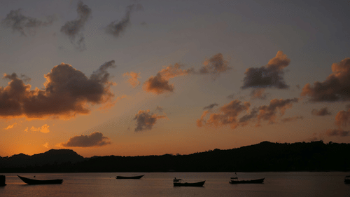 Scenic view of the ocean with boats sailing by at dusk.