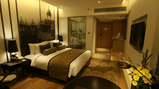 Superior Room at Pride Plaza Hotel, New Delhi featuring a king bed, bedside table on either side, a centre table, and an attached bathroom.