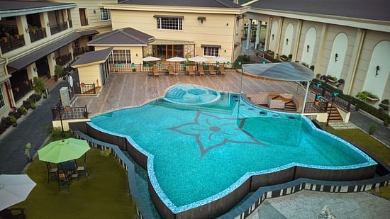 Beautifully designed outdoor swimming pool with a floral mosaic pattern, surrounded by sun loungers, shaded seating areas, and lush landscaping - Voyage The Solitaire Bliss.