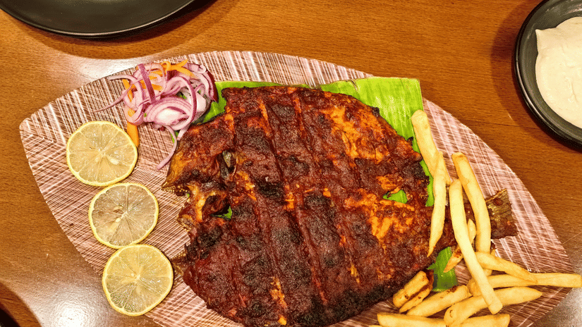 Fried fish and french fries placed on a plate shaped like a leaf.