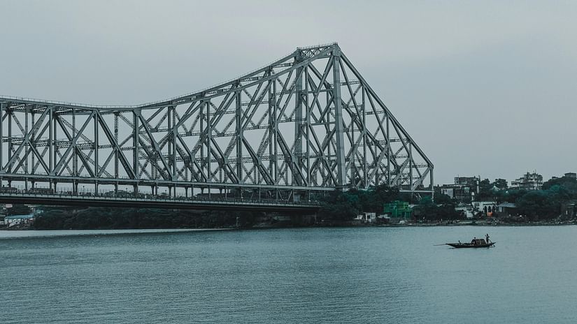 Howrah bridge above a river on a cloudy day.