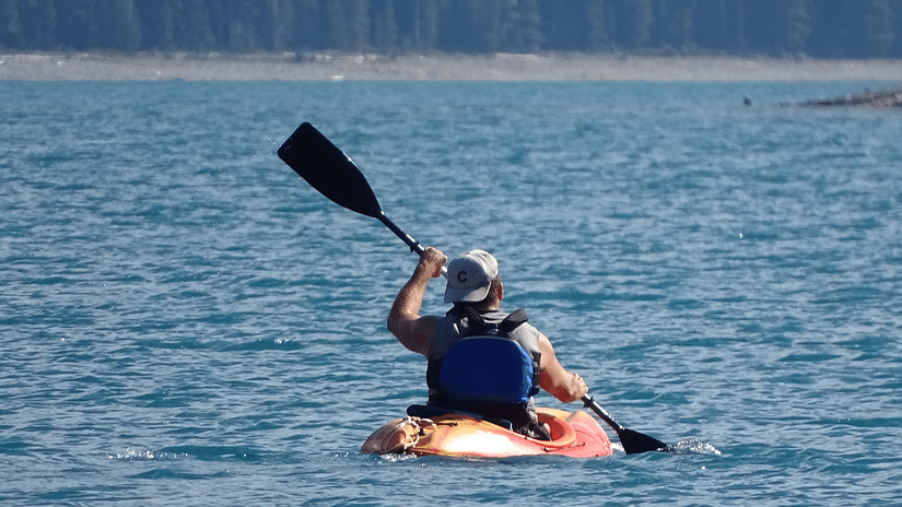 A man kayaking in a water body during the day.