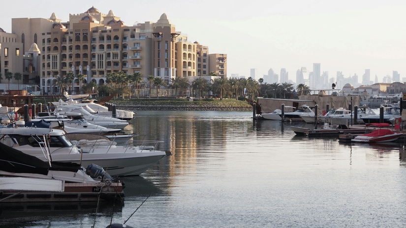 A daytime view of a marina with numerous boats docked in a waterway lined by buildings.
