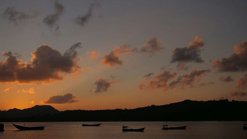 Scenic view of the ocean with boats sailing by at dusk.
