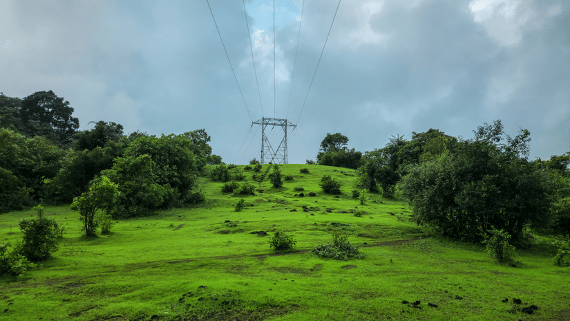An overview of the hills in Khandala with a electricity tower in the centre, surrounded by trees and greenery.