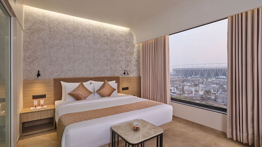 Luxury suite bedroom with city view, comfortable bed, and stylish decor - Biznotel by Pride Motera, Ahmedabad