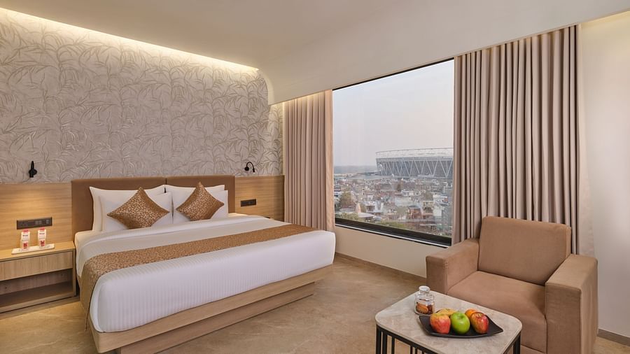 Luxurious hotel room with king bed, city view, and warm, inviting decor at Biznotel by Pride Motera, Ahmedabad
