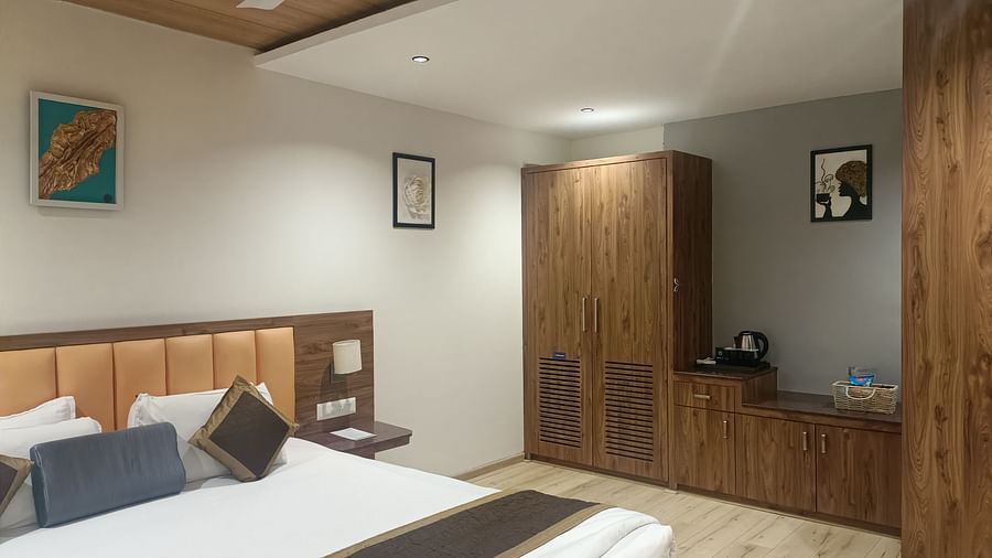 A bedroom in a Junior suite With Breakfast at Kyriad Hotel, Gulbarga, with a made bed, a ceiling fan, a wardrobe, and artwork on the wall.