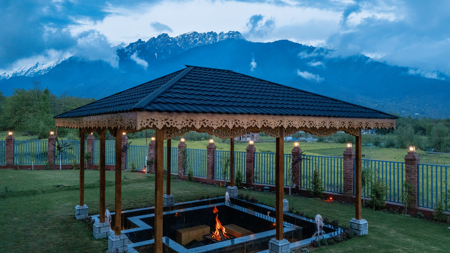 Outdoor bonfire at Mountnoor Sarovar Premiere, Pahalgam overlooking serene meadows and majestic mountains.