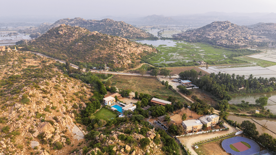 Wide aerial shot of the resort property and the rugged rocky landscape of Hampi in the distance - Nature Trails Ashoka Resort Hampi