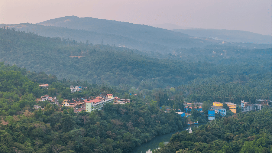 A wide view of green hills and a river under a misty sky.