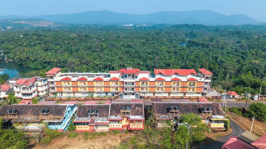 A high view of a large hotel complex with red roofs surrounded by forest.