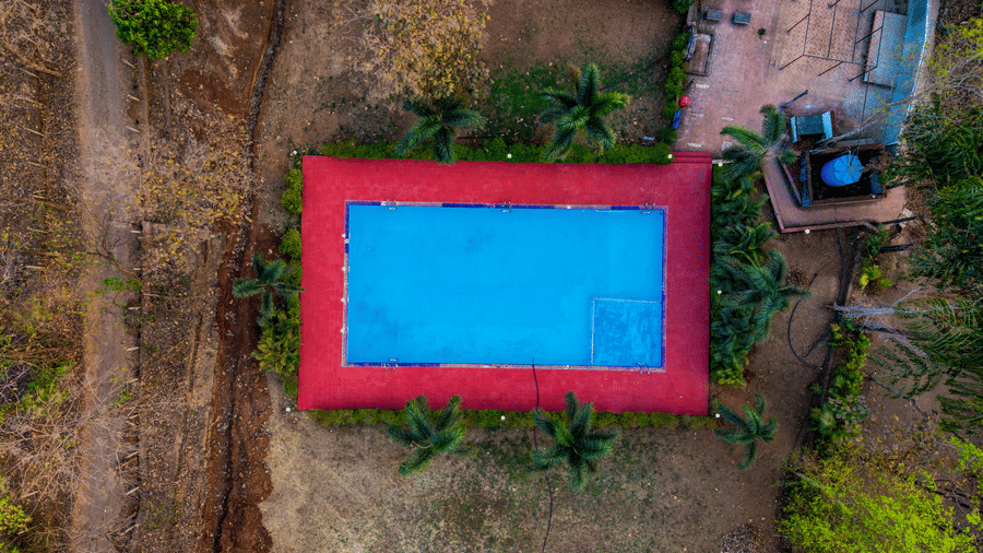 Drone view of the outdoor swimming pool and surrounding greenery at Nature Trails Sajan