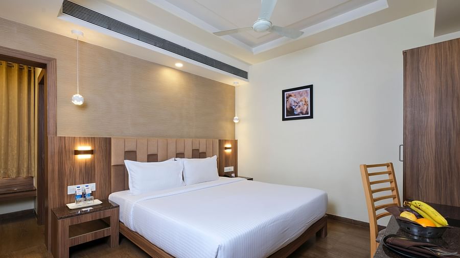 Deluxe Room at Pride Biznotel in Sasan Gir featuring a plush bed with two lamps lit over the nightstands on both sides