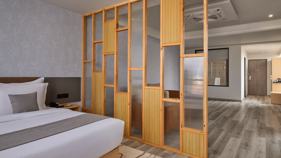 Luxury bedroom view featuring a wooden room divider and neutral tones - Pride Elite Gandhinagar