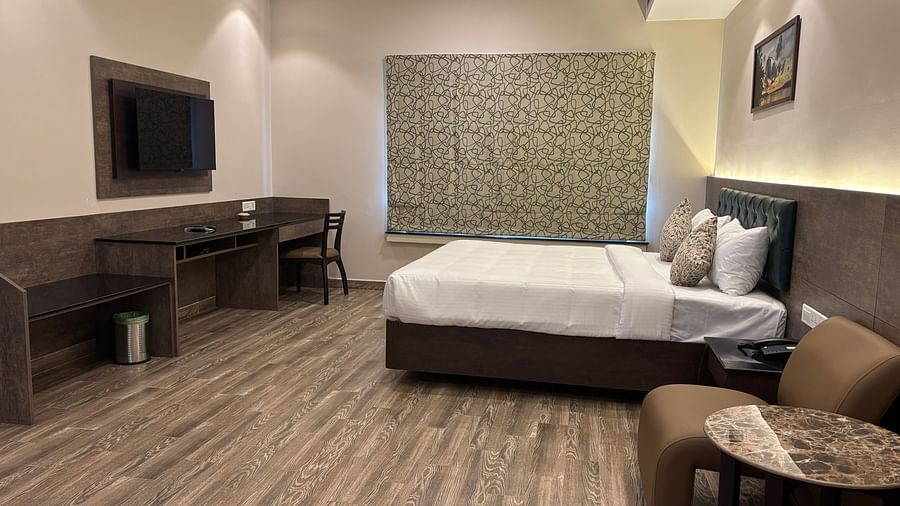 Premium Suite featuring a bed, a chair with a small table, and a window with blinds. - Still Waters, Varkala