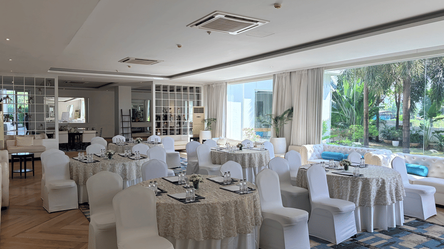 The Mansion House resort banquet hall with round tables, white-covered chairs, table settings, and large windows, creating a bright and inviting atmosphere for formal events.