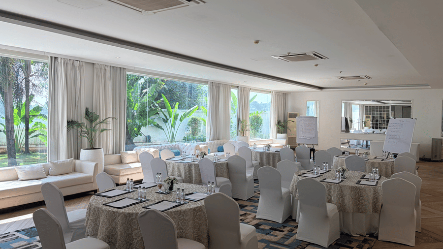 The Mansion House resort banquet setup with round tables, white-covered chairs, elegant table settings, and spacious interior, prepared for corporate events.