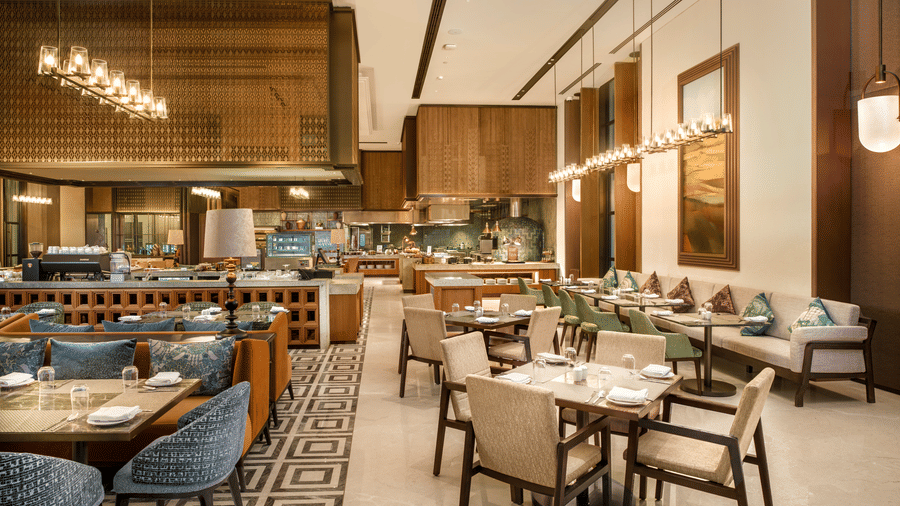 View of CHITHIRAI restaurant at The Residency Signature Madurai with dining tables, pendant lighting, wooden panelling, and warm ambient lighting.