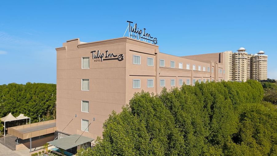 The facade of a hotel in Bhopal with trees surrounding the building - Tulip Inn, Bhopal.