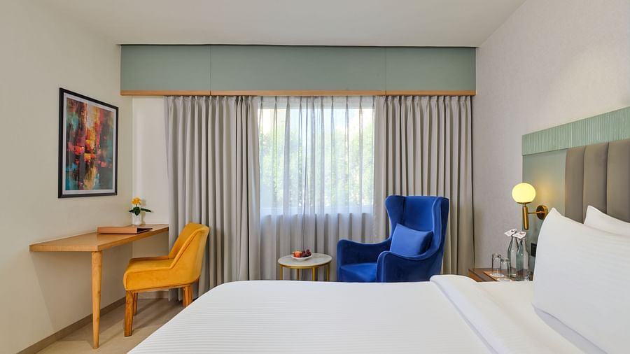 A side view of a room in Bhopal featuring a bed and a seating area situated to the side at  Tulip Inn, Bhopal.