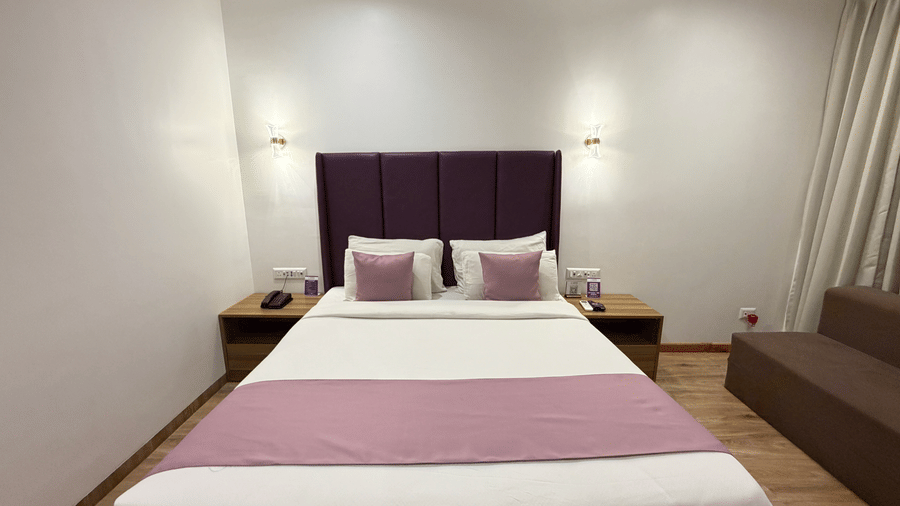 VITS Daman Devka Beach Executive Cottage with king bed, purple headboard, pink runner, wooden furniture, and soft recessed ceiling lighting throughout.