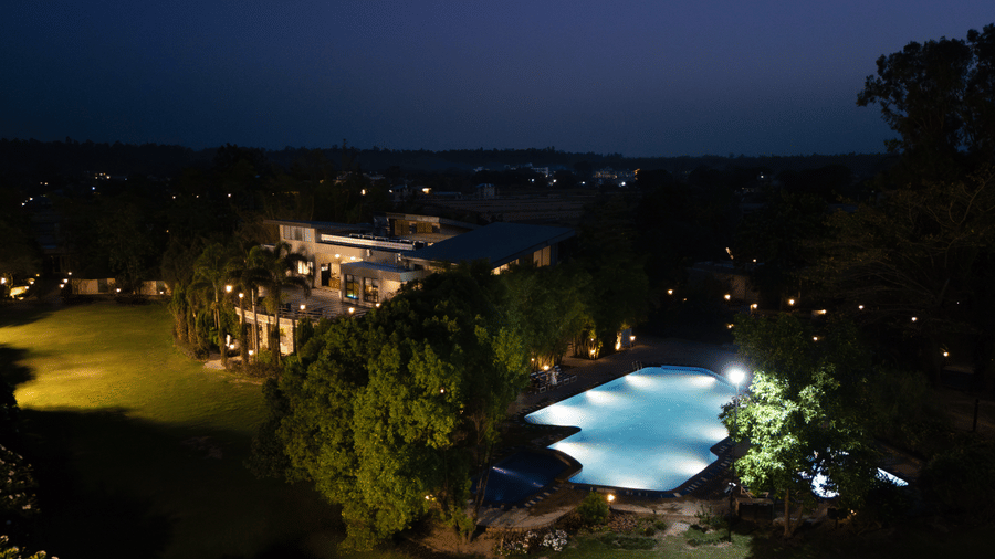 Resort with a lit-up swimming pool and surrounding landscape at The Golden Tusk, Jim Corbett