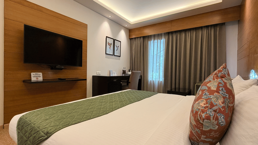 Family Room with a king bed, wall-mounted TV, and warm wooden paneling at Hotel Saket 27, offering a comfortable and modern stay.