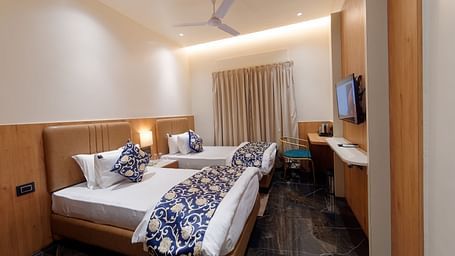 Side view of deluxe twin room with twin beds with a television in font and ceiling on the wall at Ankit Hotel, Jabalpur