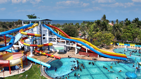 Swimming pool at MGM Dizzee World featuring several water slides which leads to a large swimming pool filled with people.