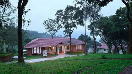 A serene view of an illuminated cottage in a lush greenery setting