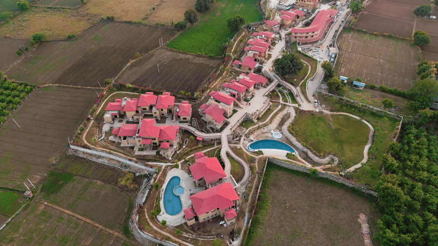An aerial view of the resort buildings nestled amongst green fields at Aamaghati Wildlife Resort.