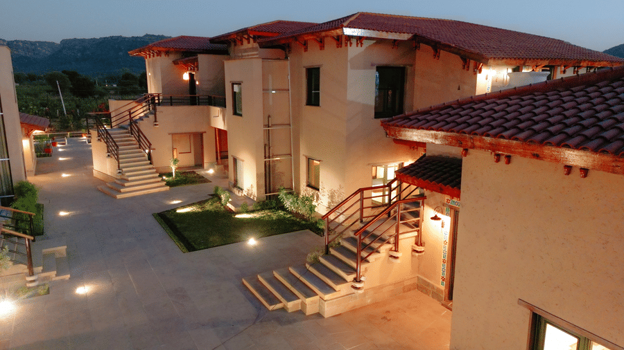 The resort buildings illuminated at dusk, showing pathways and outdoor lighting at Aamaghati Wildlife Resort.