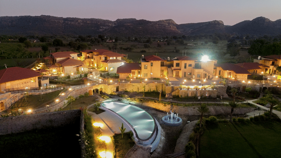 The resort buildings and illuminated swimming pool under a dark night sky at Aamaghati Wildlife Resort.