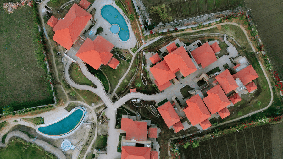 An aerial view showcasing the resort buildings with red roofs and swimming pools at Aamaghati Wildlife Resort.