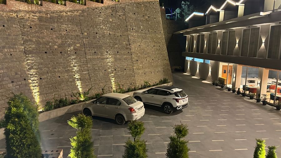 Well-lit outdoor parking area with stone wall and multiple cars parked – ARNISA Boutique Hotel