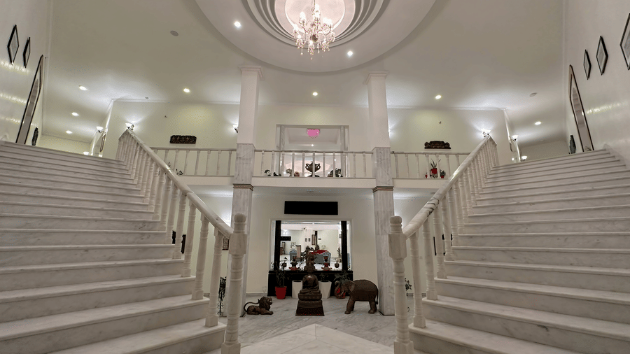 A grand staircase with elegant lighting and white interiors at AS Hotels, Khajuraho.